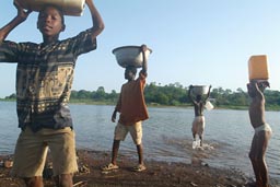 Ghana, lake and kids carry water on head.