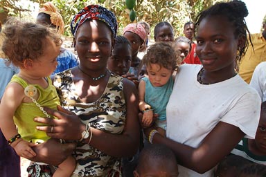 Two African women in village in Guinea Bissau hold twins Daniel and David.