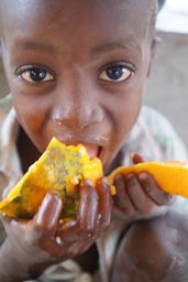 Boy eating Papaya, face, Guinea Bissau.