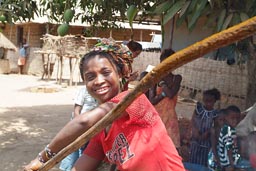 Woman and big stick steering the red palm oil brew, Guinea Bissau.