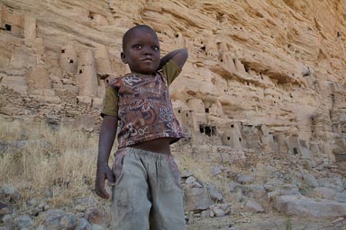 Dogon boy, in front of old Tellem and Dogon settlements in Dogon Escarpement, Irelli.