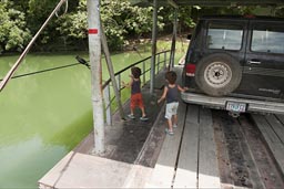 Hand pulled ferry over Mopan River to Xunantunich. 2 little boys and a van on it. Belize.