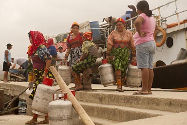 Guna women carry away gas-bottles, from commercial ship, docked on Ustupu, Guna Yala island.