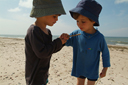 Boys in hats found a bug on beach in Latvia.