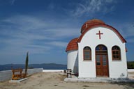 Little, white Chapel, against blue sky and water, Greece.