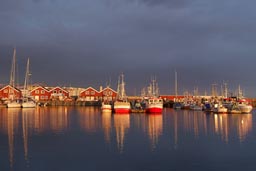 Red boats in the harbour of Bodo, Norway, lit by midnight sun.