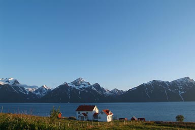 Lyngen mountains, midnight sun, white house in front of Fjord, Norway.