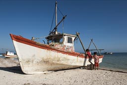Boys are mounting a fishing boat on santa Clara beach.