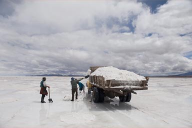 Men with shovels load an old truck on the Salare de Uyuni, Bolivia, with wet salt that sells for 4 B$ the 50 kgs.