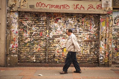 Man walks in front of shabby shop front, Bogota. 