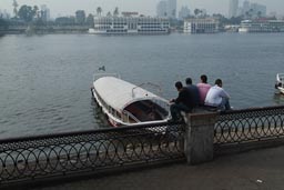 Four men sit on a railing in Cairo, looking out on Nile.