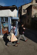 Man, veiled woman, walk past shop, Erzurum, Turkey.