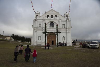 Nueva Santa Catarina Ixtahuacan. Indigenas headed for church. Overcast skies, iglesia in bright white.