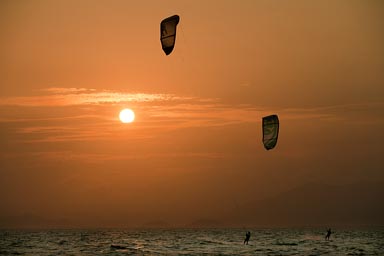 Kite surfers, Punta Chame, under an orange sunset, Panama. Pacific Ocean.