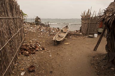 Dugout canoe and trash betwenn shags on beach in Urwargandub, Guna Yala, Panama.