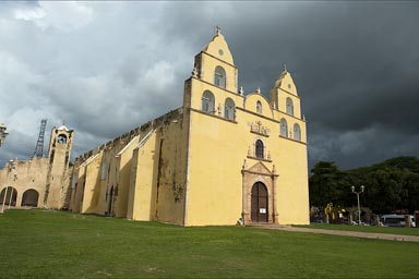 Dark clouds towering over bright yellow Oxkutzcab church.