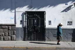 Woman walks by, white house street Cajamarca.