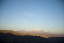 We drive high plateau in Andes and sun sets, in distance Chachani and Misti, volcanoes, Peru.